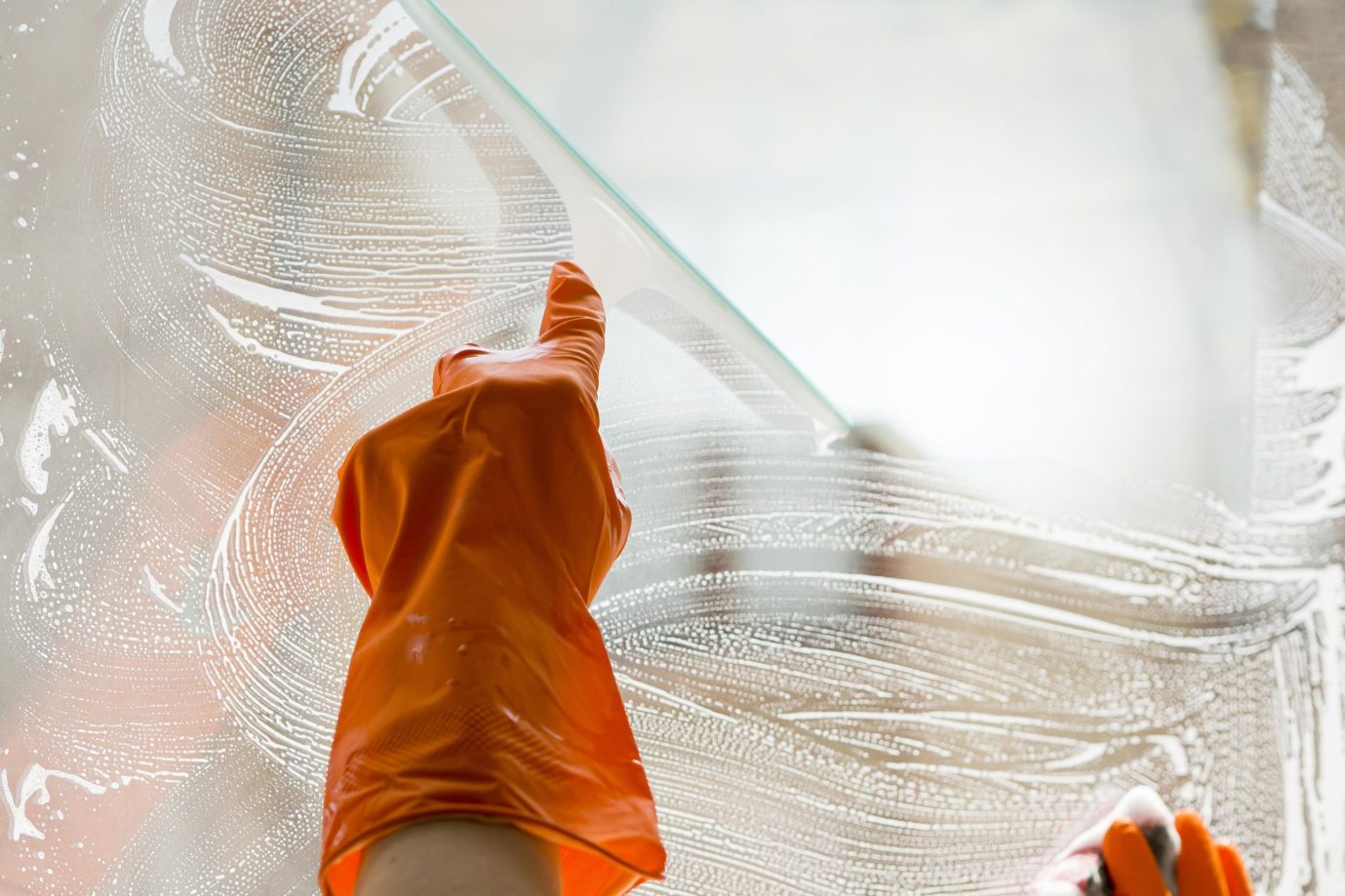 close-up-hand-with-rubber-glove-cleaning-window
