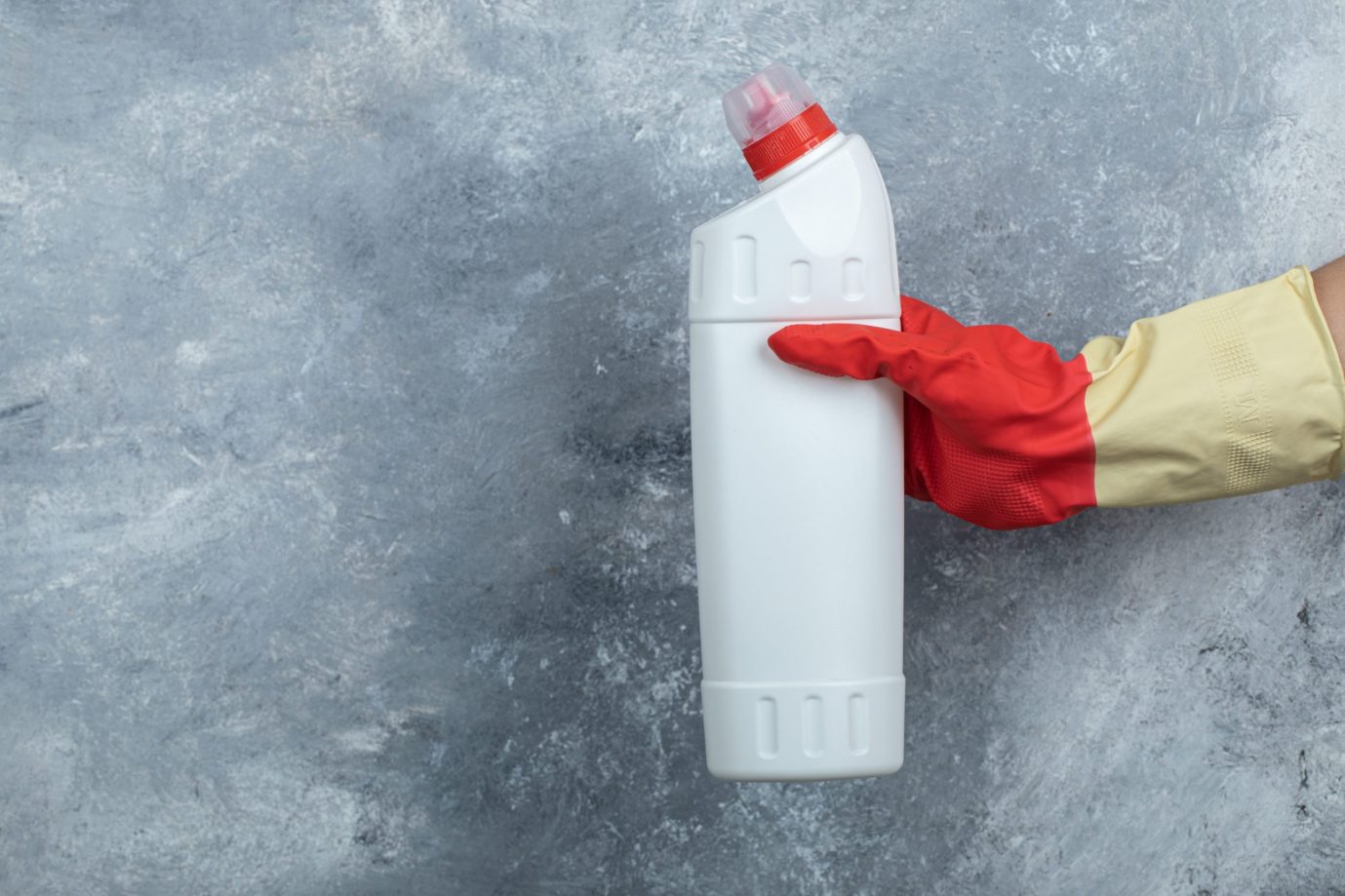Female hand holding detergent on marble background. High quality photo